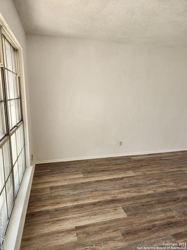 unfurnished room featuring a textured ceiling, baseboards, and wood finished floors