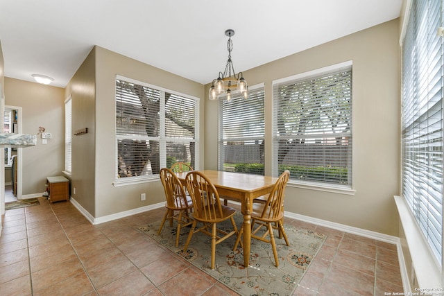 dining space featuring light tile patterned floors, plenty of natural light, baseboards, and a notable chandelier