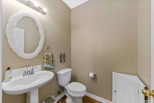 half bathroom with tile patterned flooring, baseboards, a sink, and toilet