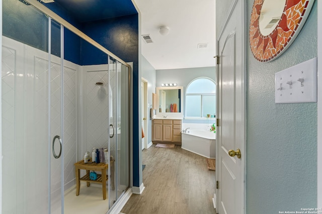 full bathroom featuring a bathtub, visible vents, a stall shower, vanity, and wood finished floors