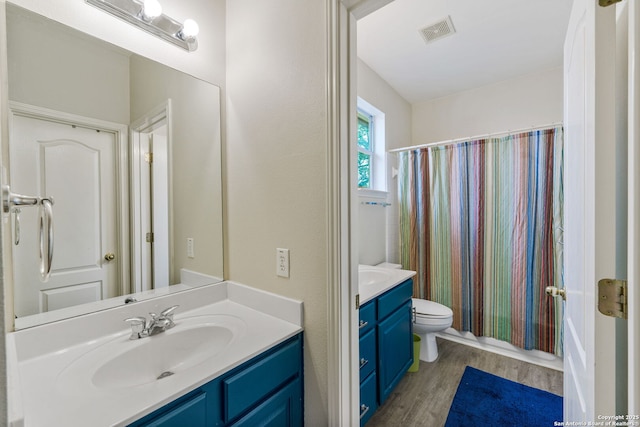 bathroom featuring toilet, visible vents, wood finished floors, and vanity