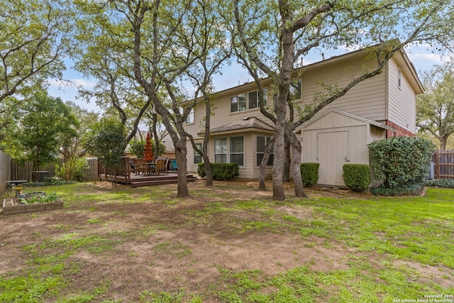 back of house featuring a storage unit, fence, a deck, a yard, and an outdoor structure