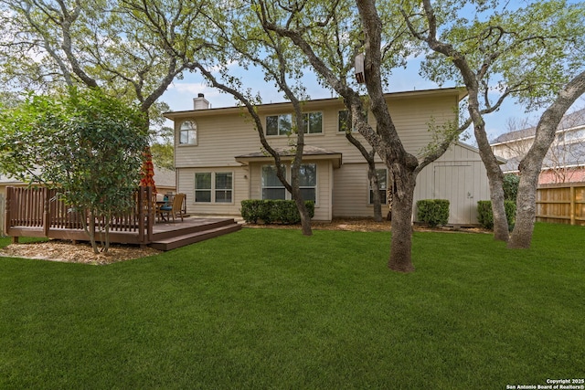 back of house featuring a deck, a chimney, fence, and a lawn