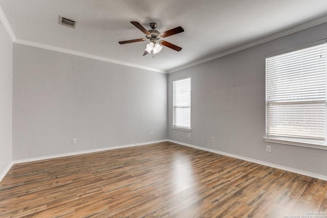 spare room featuring crown molding, visible vents, ceiling fan, wood finished floors, and baseboards