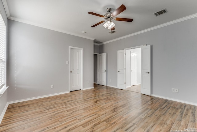 unfurnished bedroom featuring baseboards, light wood-style flooring, visible vents, and crown molding