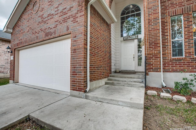 property entrance with brick siding, driveway, and an attached garage