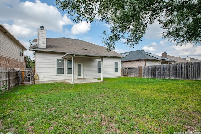 rear view of property featuring a yard, a chimney, a patio area, and a fenced backyard