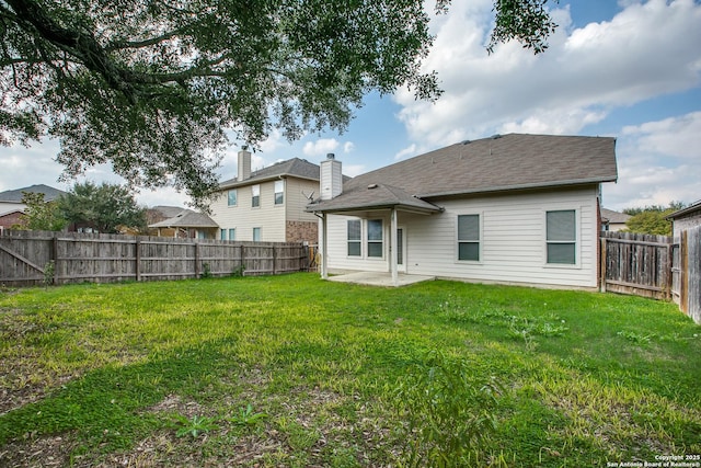 back of house featuring a patio area, a fenced backyard, a shingled roof, and a yard