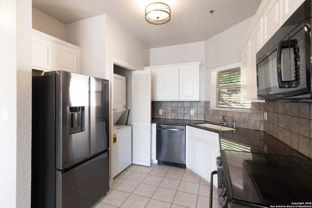 kitchen featuring light tile patterned floors, decorative backsplash, appliances with stainless steel finishes, white cabinetry, and a sink