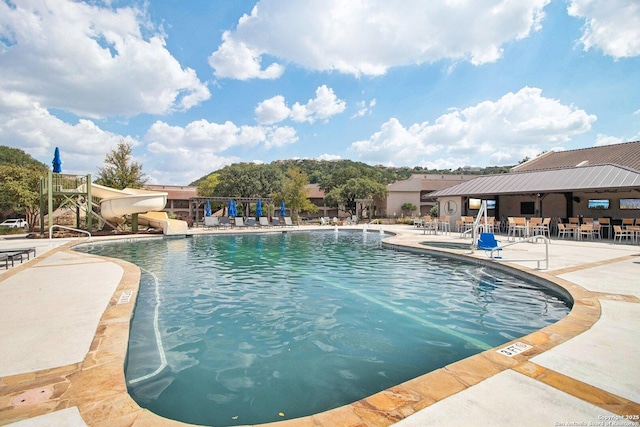 pool featuring a water slide and a patio