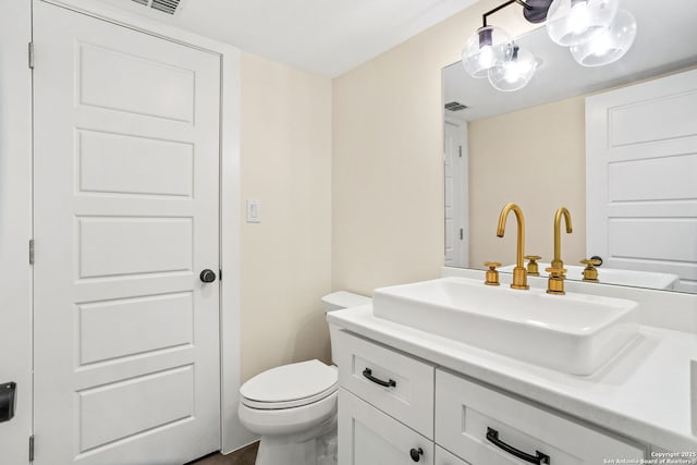 half bathroom with visible vents, vanity, and toilet