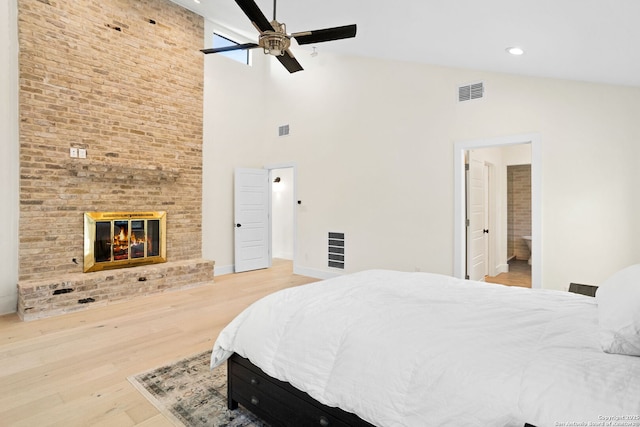 bedroom featuring a brick fireplace, visible vents, vaulted ceiling, and wood finished floors