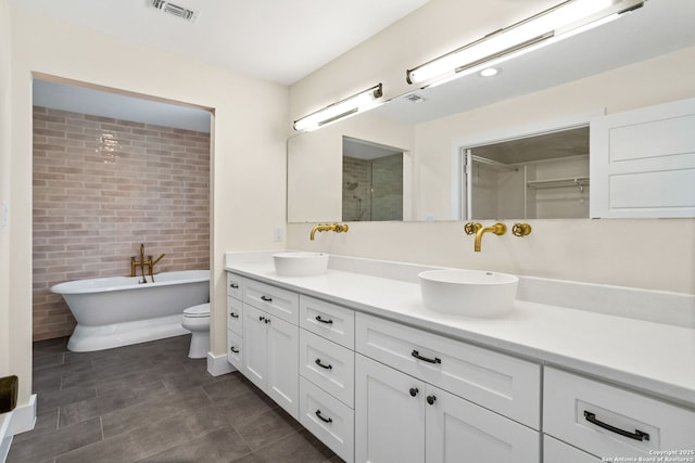 full bathroom with a freestanding tub, visible vents, a sink, and double vanity