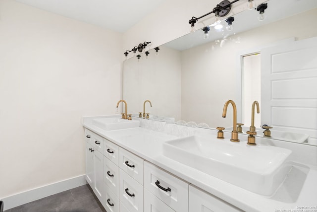 full bathroom with double vanity, tile patterned floors, a sink, and baseboards