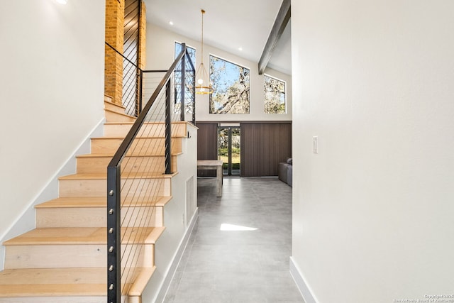 staircase featuring finished concrete flooring, recessed lighting, a high ceiling, a chandelier, and baseboards