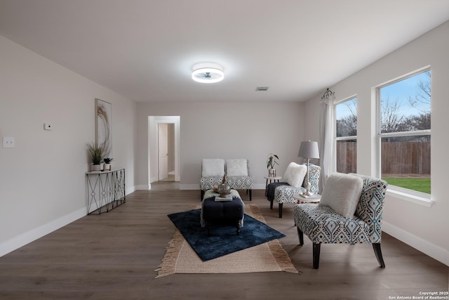 sitting room with baseboards, visible vents, and wood finished floors