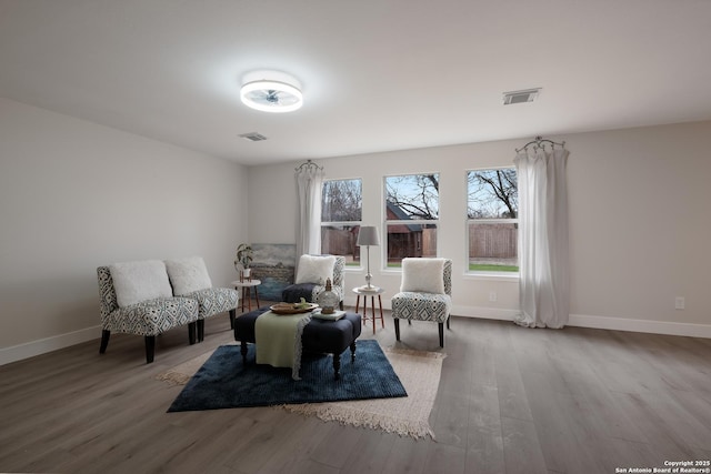 sitting room with baseboards, visible vents, and wood finished floors