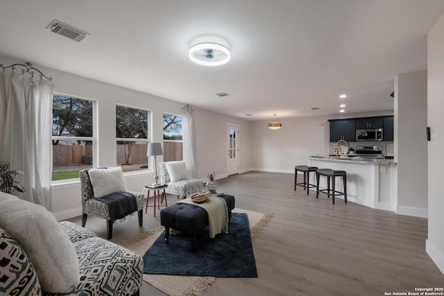 living room with recessed lighting, baseboards, visible vents, and light wood finished floors