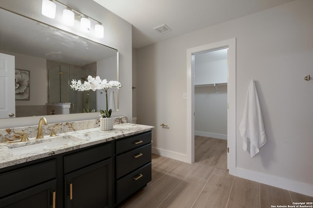 full bath with wood finish floors, vanity, visible vents, baseboards, and a shower stall