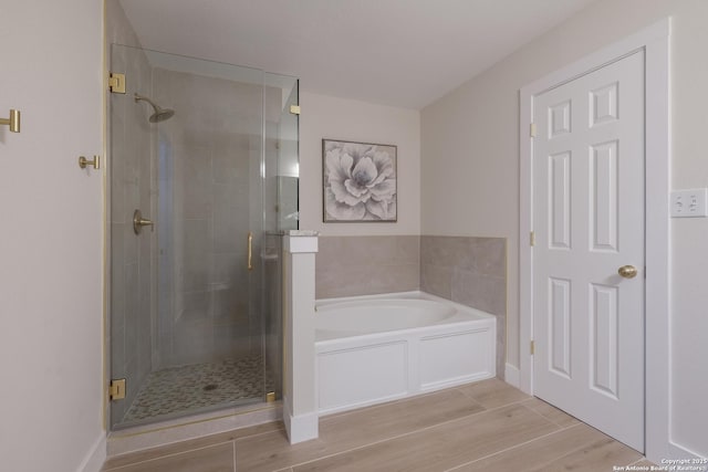 bathroom with a garden tub, a shower stall, and wood finished floors