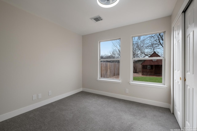 empty room featuring carpet floors, visible vents, and baseboards