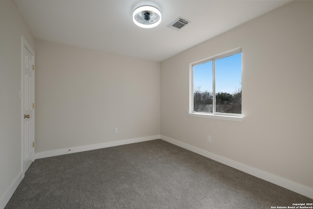 empty room featuring dark colored carpet, visible vents, and baseboards