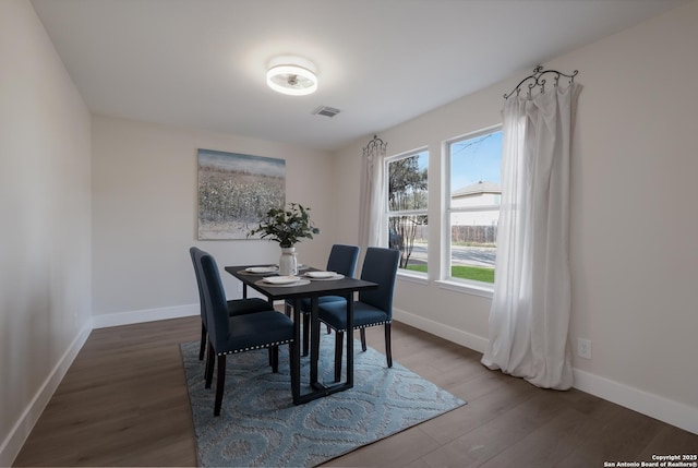 dining room with dark wood-type flooring, visible vents, and baseboards