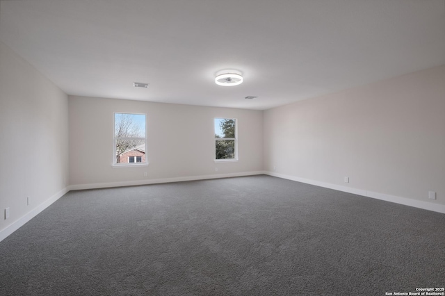 spare room with visible vents, baseboards, and dark colored carpet