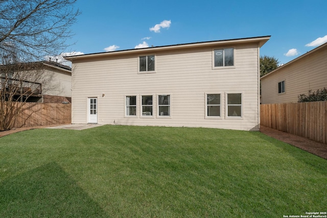 rear view of property with a fenced backyard and a yard