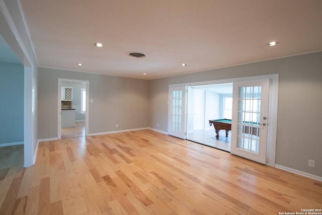 empty room with light wood-type flooring, baseboards, visible vents, and ornamental molding