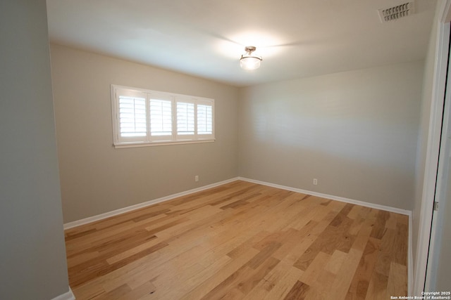 empty room with visible vents, light wood-style flooring, and baseboards