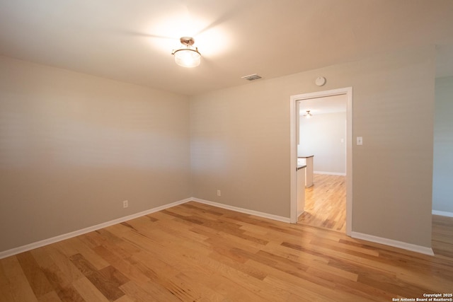 unfurnished room featuring visible vents, light wood-style flooring, and baseboards