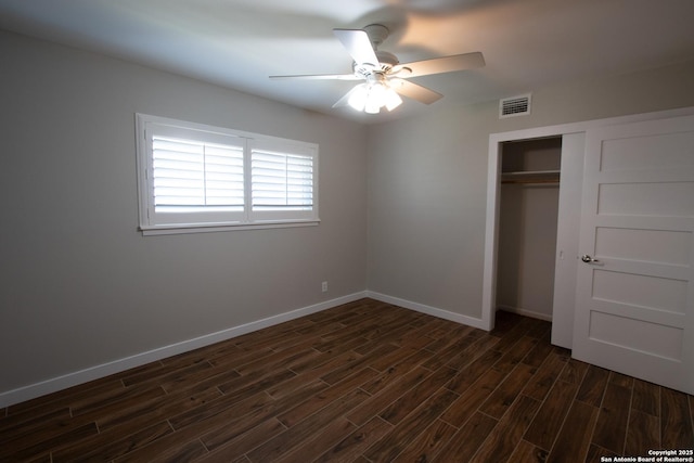 unfurnished bedroom with dark wood-type flooring, a closet, visible vents, and baseboards