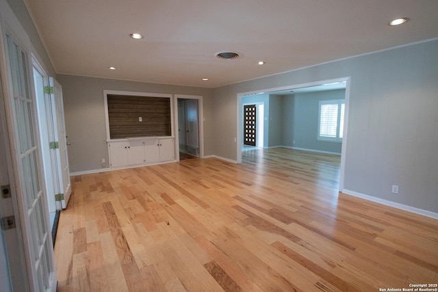 unfurnished room featuring light wood-style flooring, visible vents, baseboards, and ornamental molding