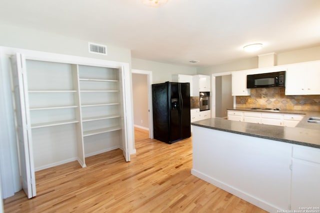 kitchen with dark countertops, black appliances, visible vents, and white cabinets