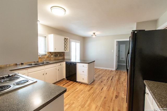 kitchen with dark countertops, black appliances, a peninsula, and a sink