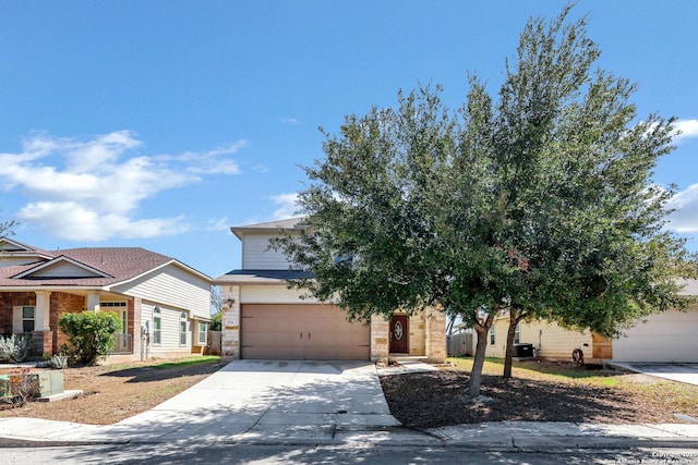 view of property hidden behind natural elements with stone siding, an attached garage, and concrete driveway