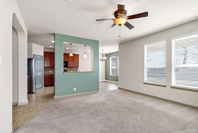 unfurnished living room featuring light tile patterned floors, recessed lighting, ceiling fan with notable chandelier, light colored carpet, and baseboards