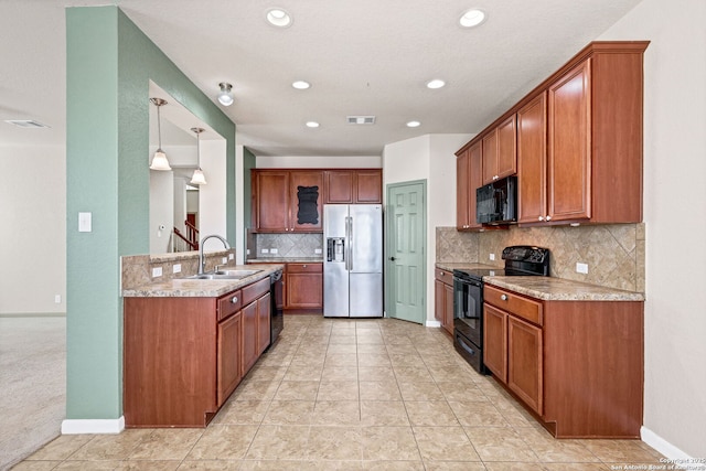 kitchen featuring visible vents, brown cabinetry, a sink, black appliances, and baseboards