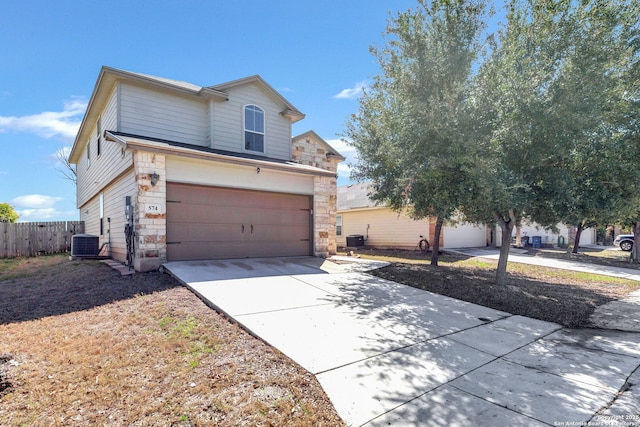 traditional-style home featuring driveway, a garage, central AC unit, stone siding, and fence