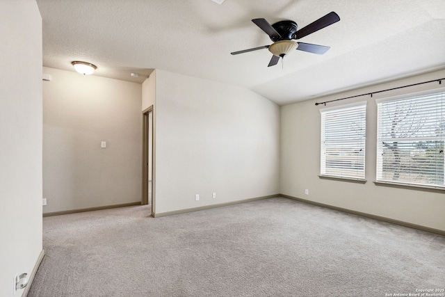 carpeted empty room with vaulted ceiling, ceiling fan, a textured ceiling, and baseboards