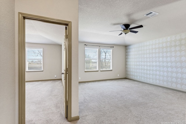 unfurnished room featuring wallpapered walls, visible vents, baseboards, carpet, and a textured ceiling