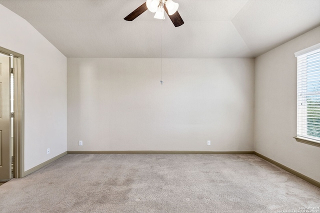 carpeted spare room with baseboards, vaulted ceiling, and a ceiling fan