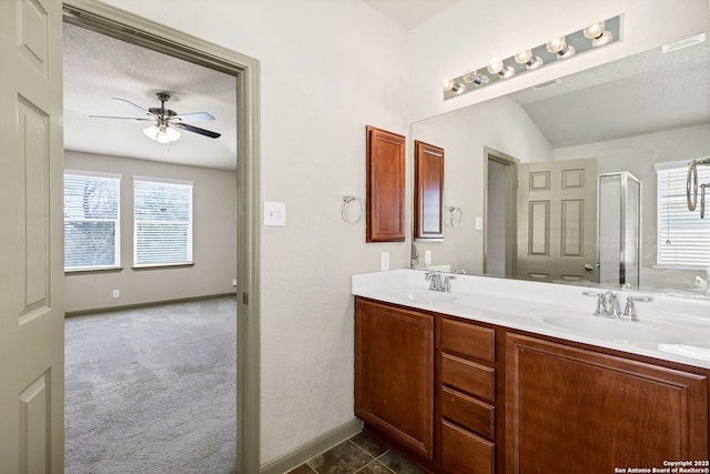 bathroom featuring double vanity, a shower with shower door, a sink, and a ceiling fan