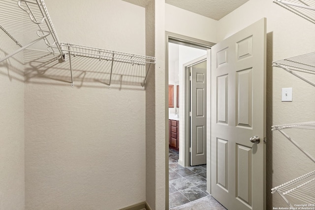 walk in closet featuring stone finish flooring