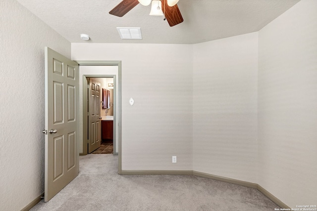 unfurnished room with light colored carpet, visible vents, ceiling fan, a textured ceiling, and baseboards