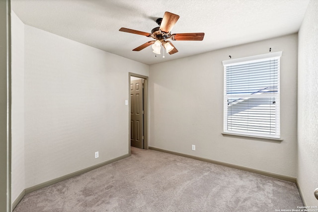 empty room featuring a textured ceiling, baseboards, a ceiling fan, and light colored carpet