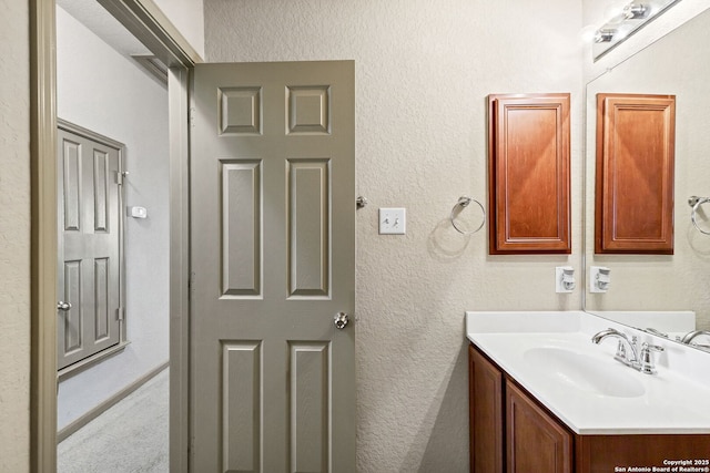 bathroom featuring a textured wall and vanity