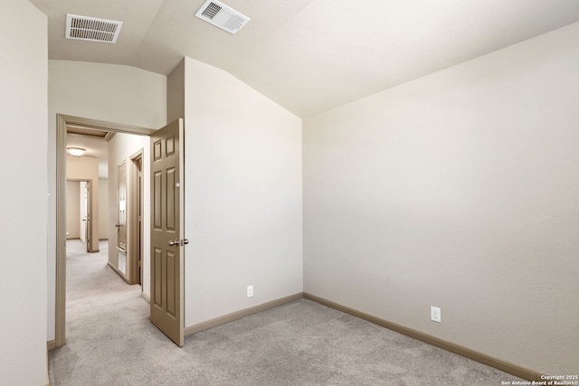 spare room featuring light colored carpet, visible vents, and lofted ceiling