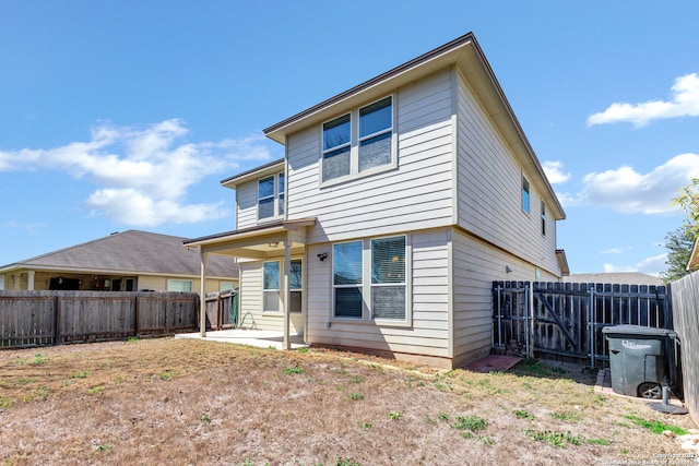 back of house with a fenced backyard and a patio